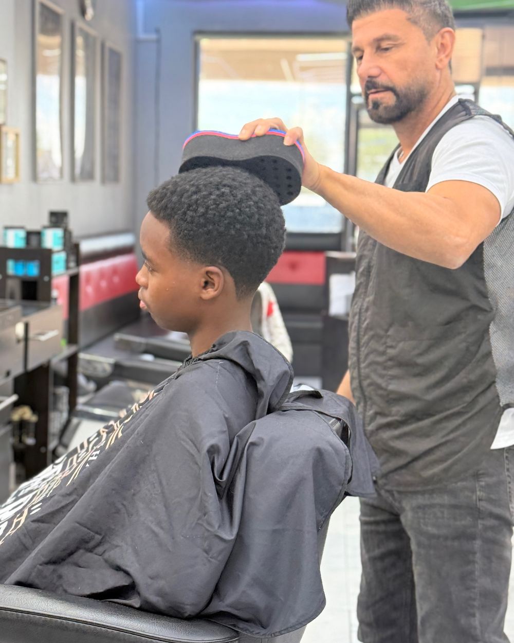 A barber finishing a kid's haircut in the chair